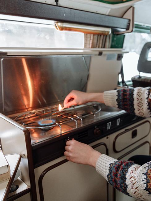 personne entrain d'allumer la cuisimière dans un van