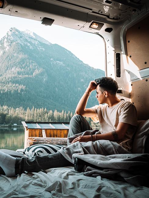 personne dans un van aménagé regardant les montagnes