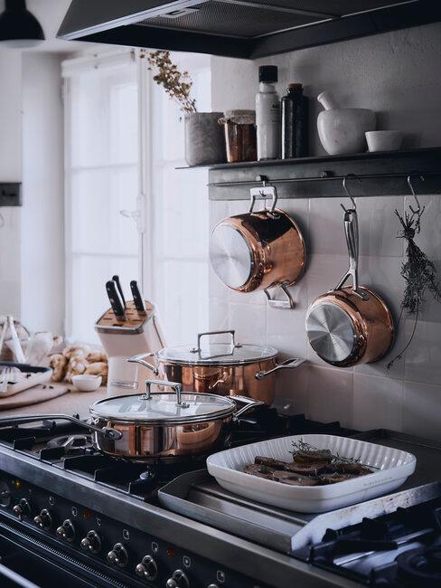 cuisinière noire, casseroles en cuivre et plat blanc pour batch cooking
