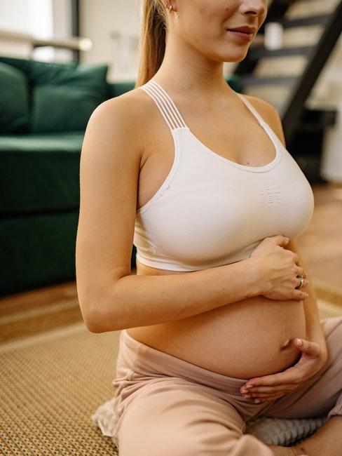 une femme enceinte tient son ventre avec ses deux mains