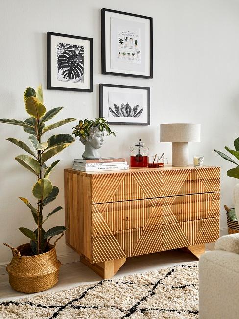 plante dans un cache-pot, cadres déco au mur, commode en bois massif clair, lampe beige rétro