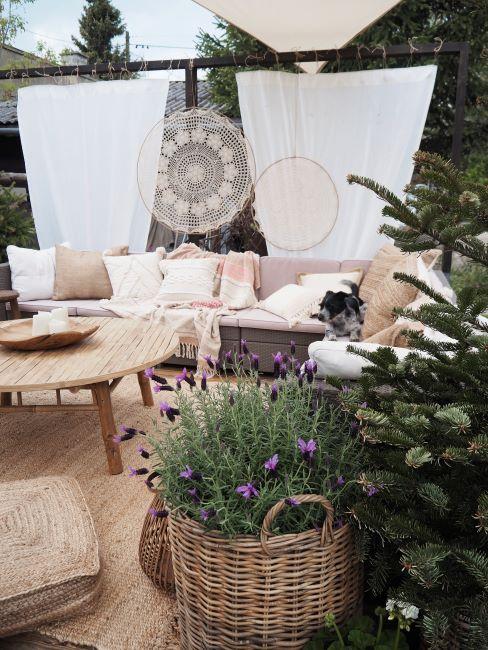 balcon avec un grand canapé extérieur et des rideaux opaques avec macramés, des fleurs de lavande