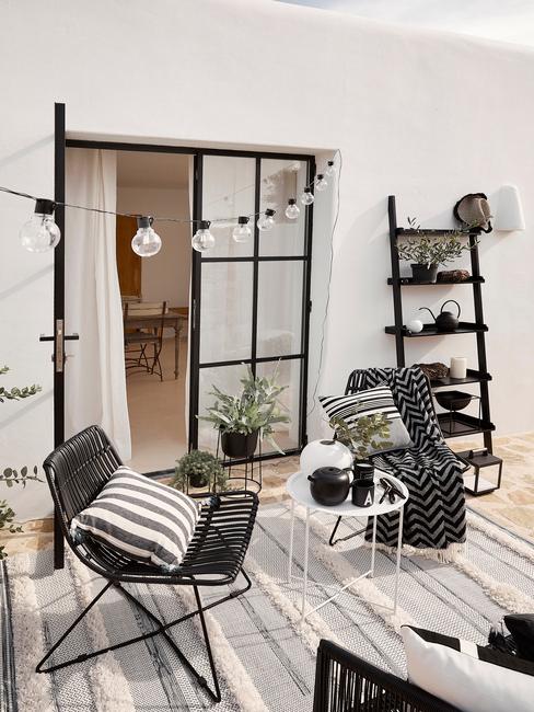 terrasse épurée avec mur blanc, échelle noire, guirlande lumineuse et plantes