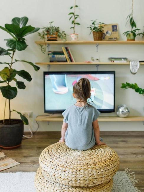 petite fille dans le salon; assise devant la TV avec des étagères DIY