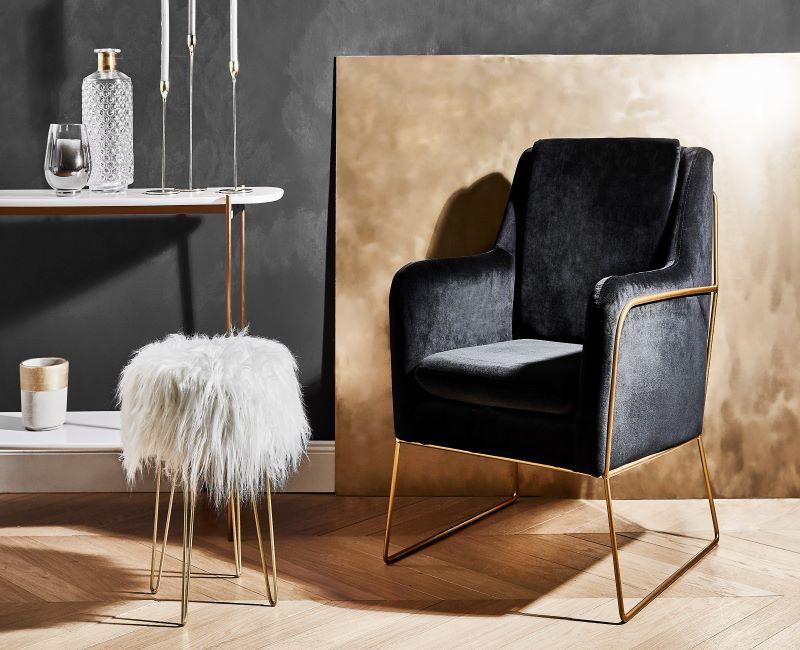 tabouret avec pieds dorés, peau de mouton naturelle, fauteuil noir, murs gris