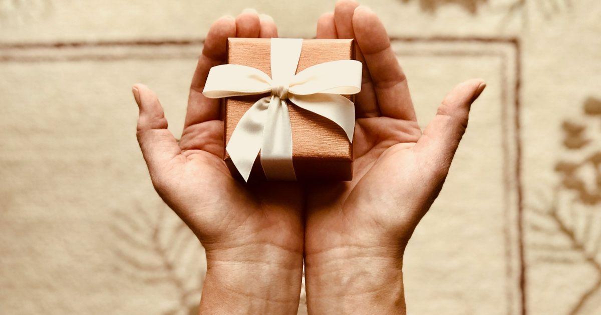cadeau emballé en papier kraft et tenu entre les mains