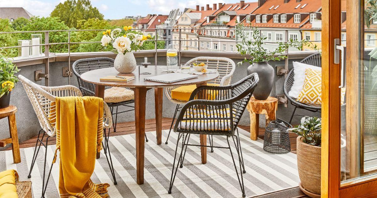 décoration balcon dans les tons moutarde, bois, chaises et tables en fer forgé, vue sur les toits