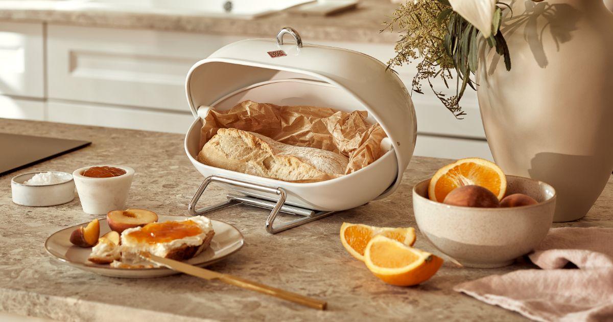 pain dans boite à pain métalique sur plan de travail en marbre marron, prune et orange