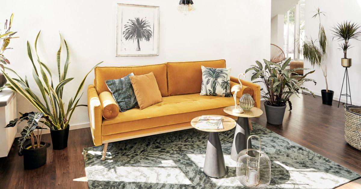 salon avec murs blanc, sol en parquet foncé, canapé moutarde et plantes