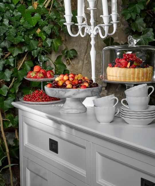 commode blanche avec fruits et gâteaux aux fruits frais, chandelier blanc