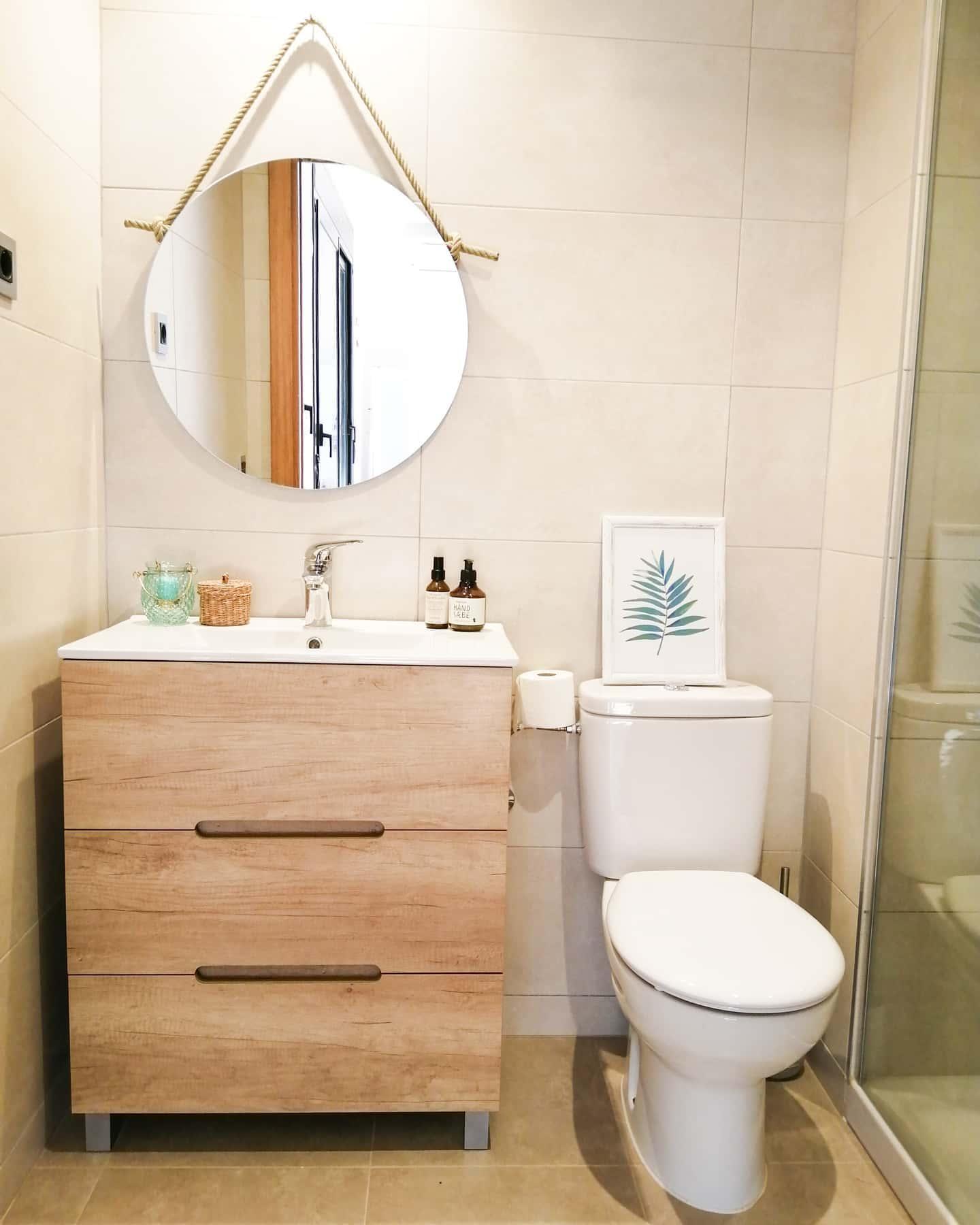 toilettes beiges avec meuble de vasque en bois et miroir suspendu rond