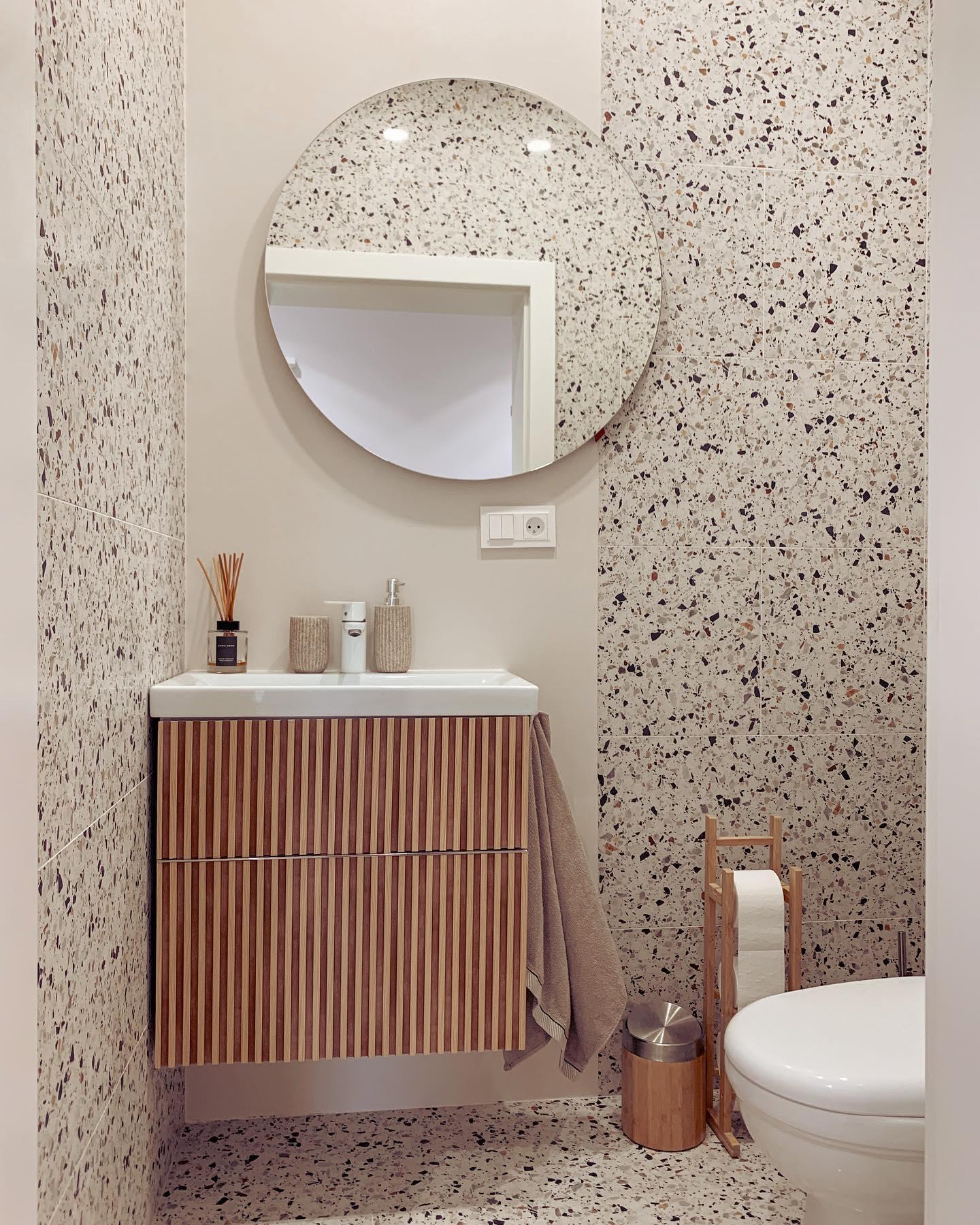 toilettes blanches avec du carrelage mural à motifs gris et noir et un meuble de vasque en bois