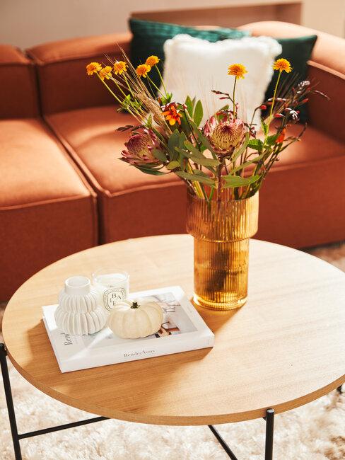 canapé couleur terracotta et un vase de fleurs posé sur une table basse en bois