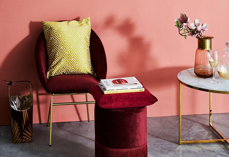 salon rose avec fauteuil rouge bordeaux et coussins et tabouret bordeaux