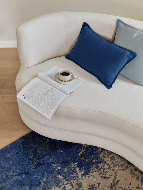 canapé arrondi Solomon beige, coussins bleus, tasse de café