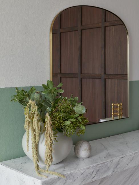 mur vert de gris, miroir, vases et fleurs vertes