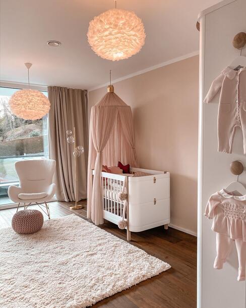 chambre de bébé fille, suspensions en plumes, lit blanc à baldaquins rose, tapis épais blanc