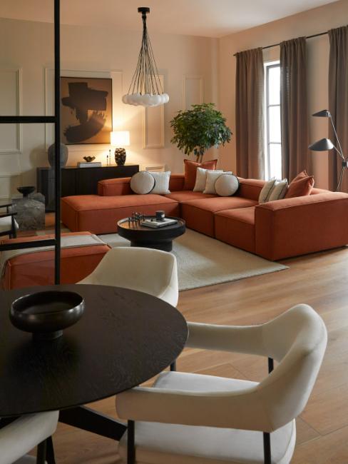 salon salle à manger vu du coin repas, table ronde, chaises blanches et canapé d'angle terracotta