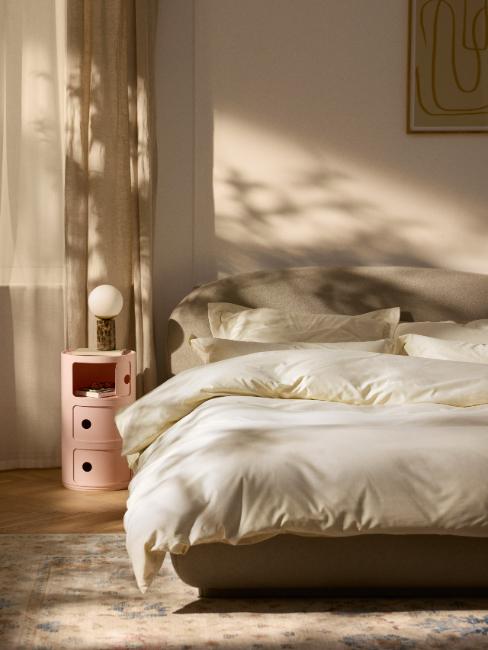 caisson de rangement componibili de Kartell rose à côté d'un lit