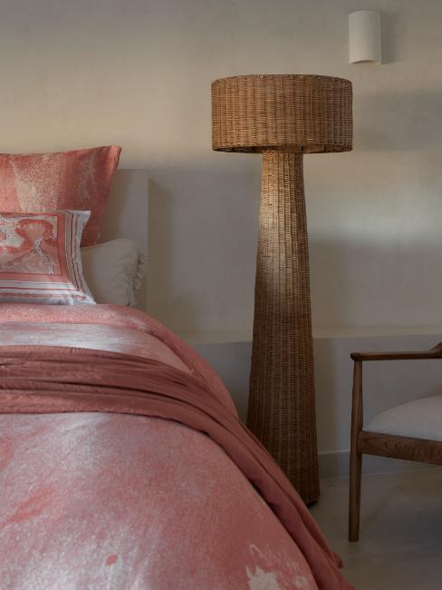 lampadaire en rotin vintage à côté d'un lit
