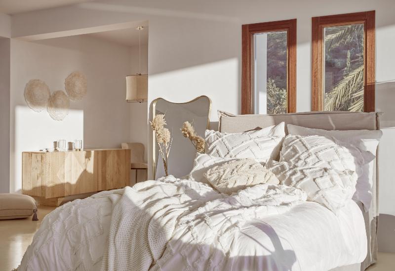 chambre bohème scandinave avec linge de lit abondant en coton tufté