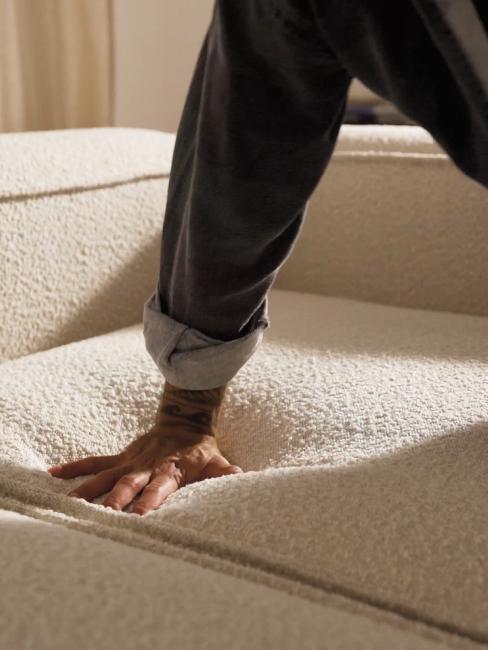 main appuyant sur l'assise d'un canapé d'une densité de 35 kg/m3