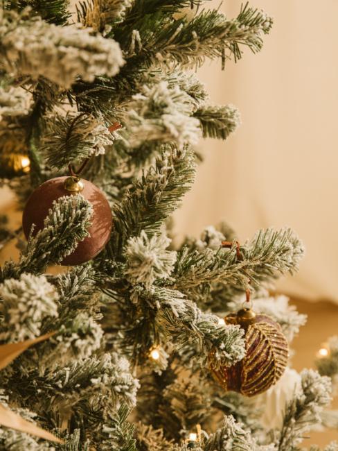boule de noël en fibre naturelle beige sur un sapin enneigé