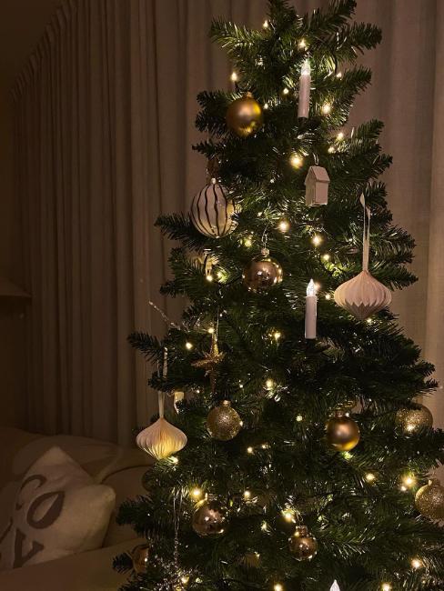 sapin artificiel décoré en blanc et doré avec des bougies à LED et des boules en papier