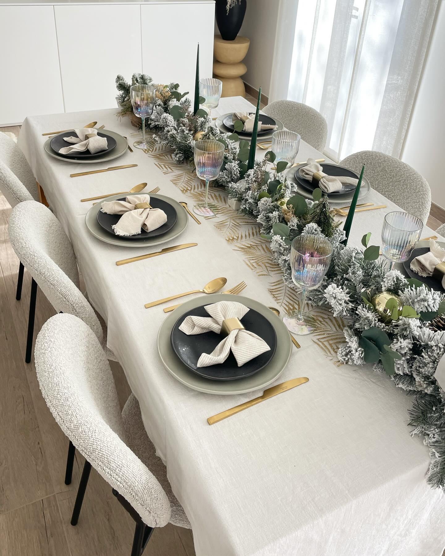 table avec nappe blanche, couverts doré et chemin de table en sapin enneigé