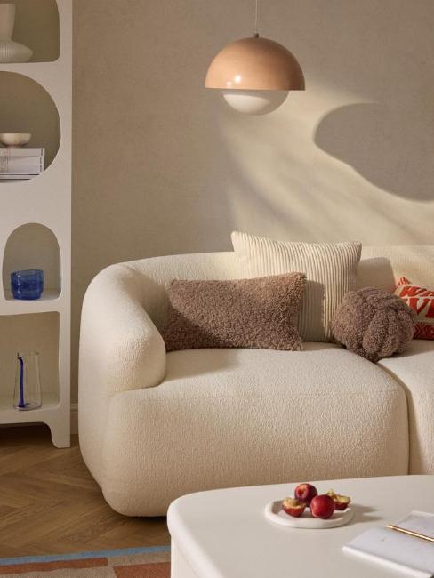 coussins en tissu bouclette sur canapé arrondi blanc crème