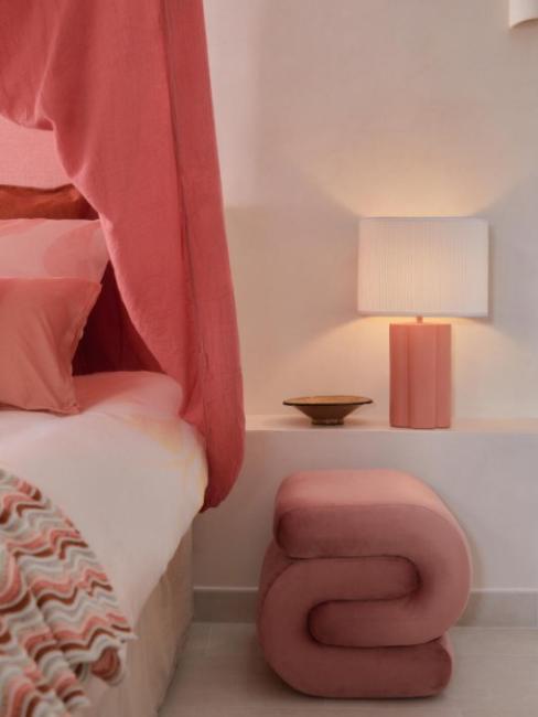 pouf design en velours couleur corail à côté d'un lit à baldaquin et d'une lampe assortis