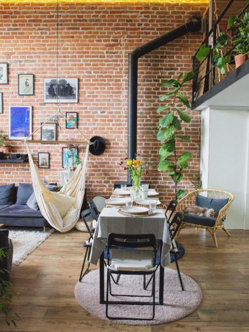 salon industriel avec plantes, hamac et mur en brique