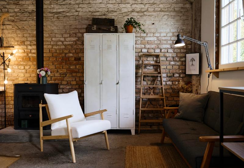 salon industriel avec grand casier en métal, fauteuil en bois et applique murale de dessinateur