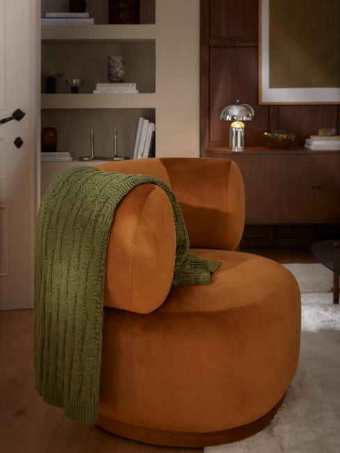plaid vert olive sur un fauteuil rétro cognac