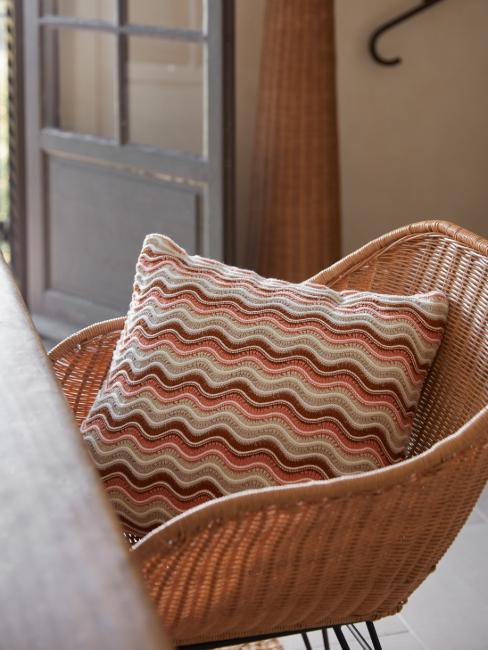chaise en rotin et coussin en tricot orange et blanc