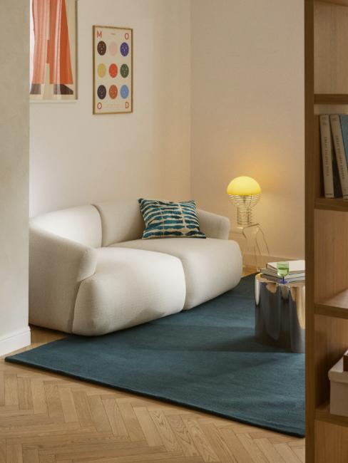 petit salon avec canapé blanc, tapis et coussin bleu canard