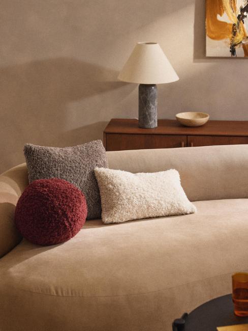 canapé arrondi beige avec coussin boule couleur bordeaux