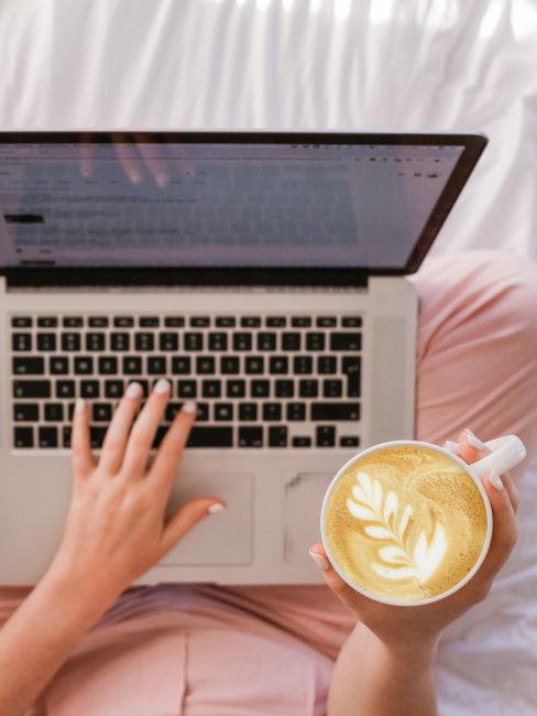 mano di ragazza che scrive a computer e beve cappuccino