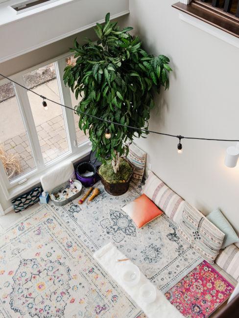 stanza vista dall'alto con tappeti, cuscini e piante