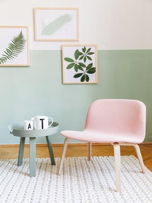Serie di quadri su muro bicolore chiaro con poltrona rosa e tavolino da caffe