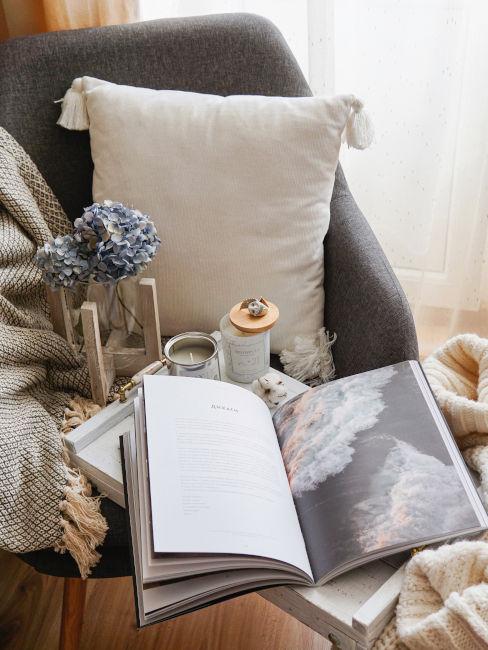libro aperto appoggiatosu poltrona con cuscino e coperta