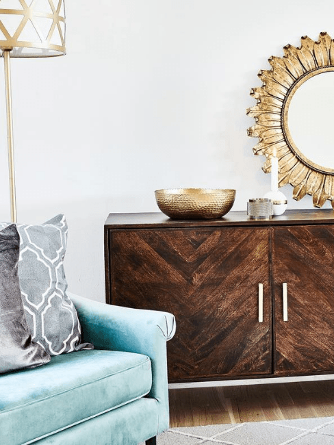 consolle in legno scuro con decorazioni oro e poltrona azzurra