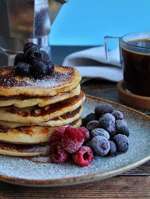 primo piano di pancake proteici con frutta e tazza di caffè