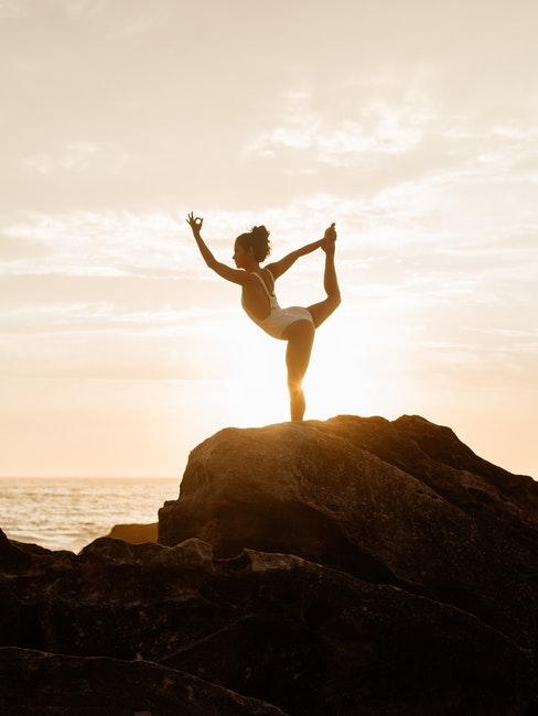 benefici yoga ragazza in costume bianco che pratica yoga al mare