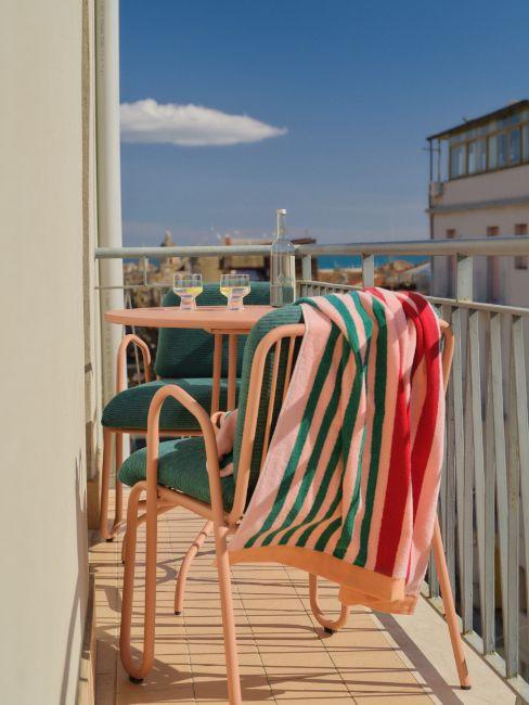 balcone stretto e lungo con tavolo e sedie rosa