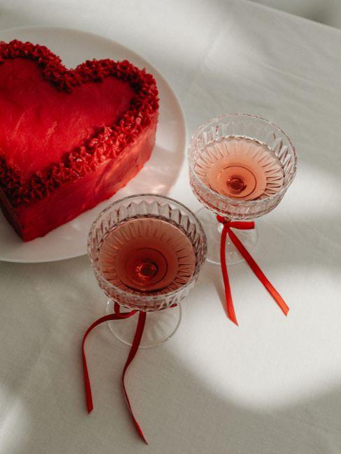 torta a forma di cuore e bicchieri con fiocco rosso