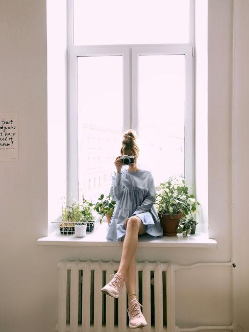 ragazza seduta su finestra con vestito azzurro