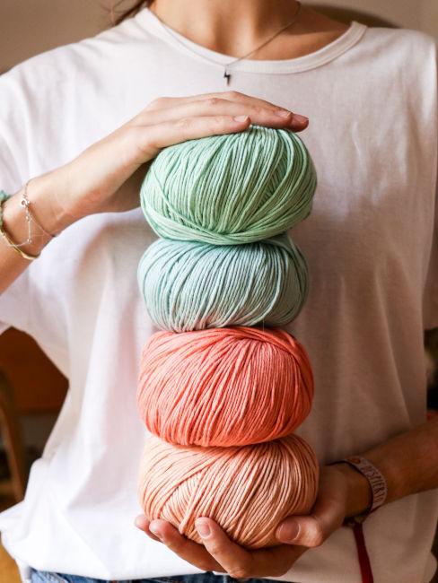 mani di ragazza che tengono gomitoli di cotone colorati