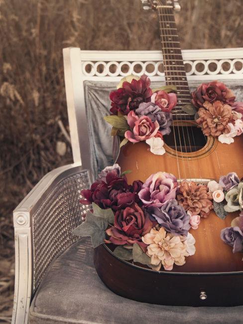 chitarra decorata con fiori appoggiata su una sedia