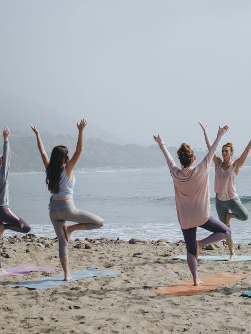 gruppo di donne che fa yoga in spiaggia
